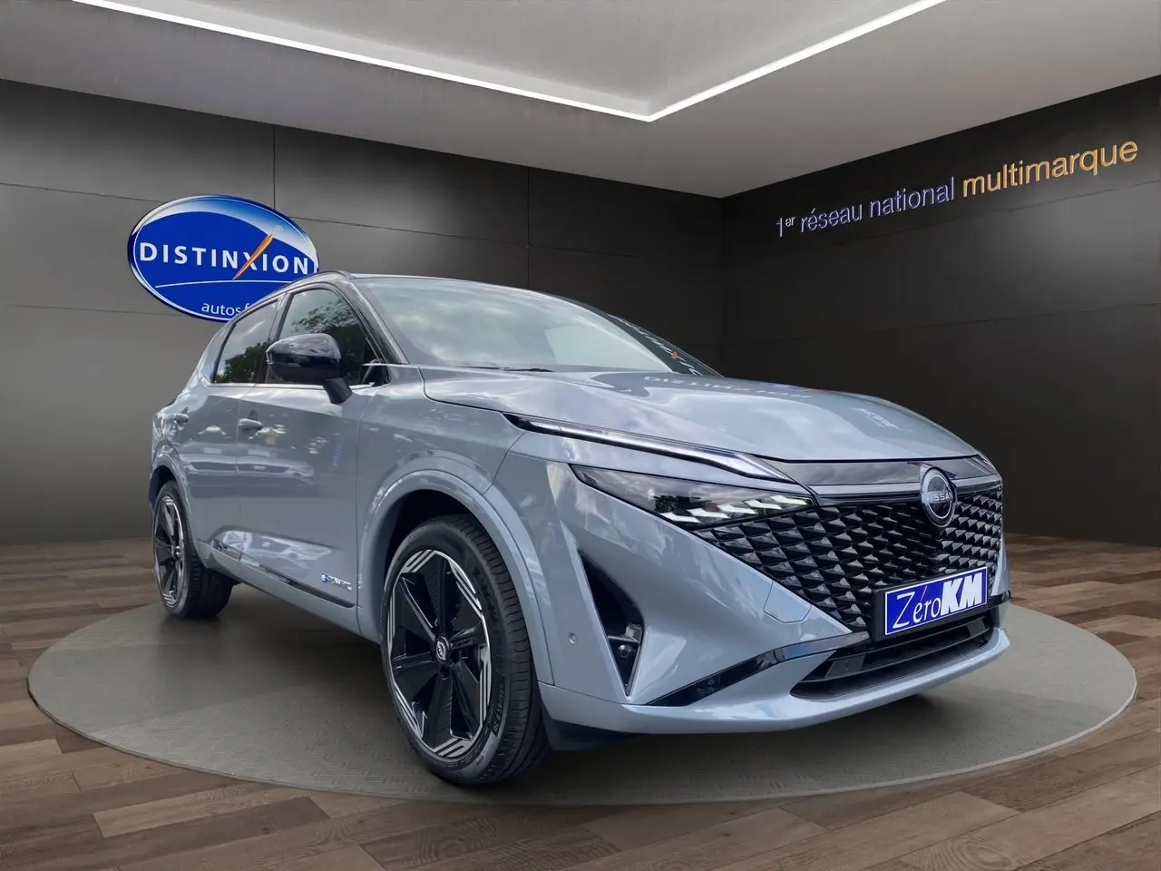 Nissan Qashqai 2025 gris ceramic et noir, vue 3/4 avant avec calandre noire et jantes noires distinctives.