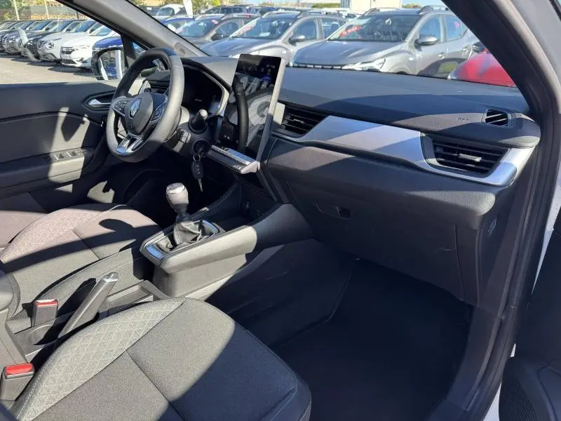 Intérieur avant droit du Renault Captur noir 2025, avec tableau de bord moderne et levier de vitesse manuel visible.