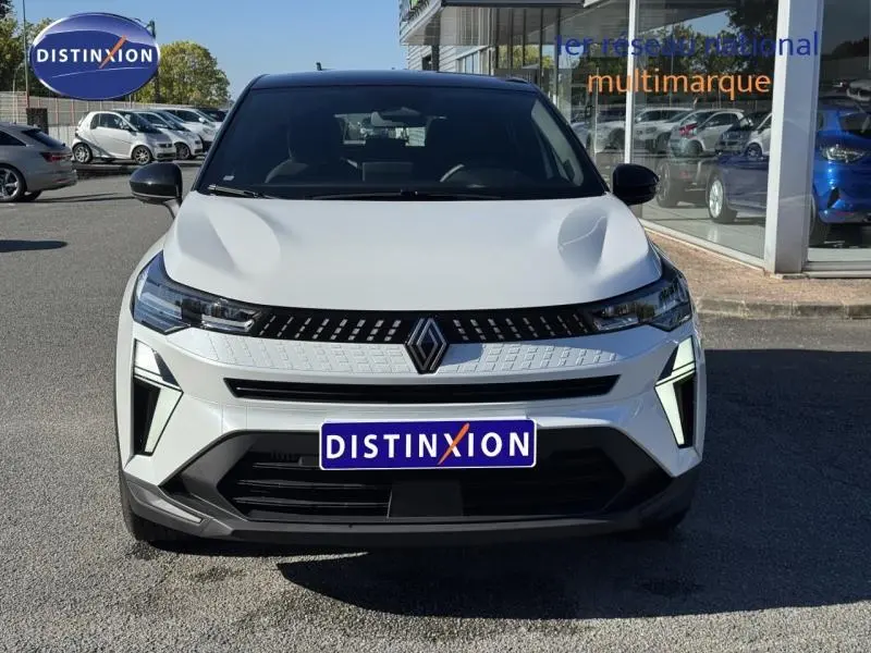 Vue frontale d'un Renault Captur 2025 blanc avec toit noir, mettant en valeur sa calandre moderne et ses phares LED distinctifs.