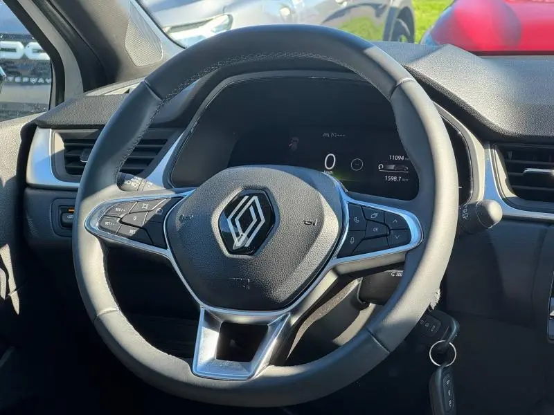 Vue rapprochée du volant noir du Renault Captur 2025, avec commandes intégrées et tableau de bord numérique visible.