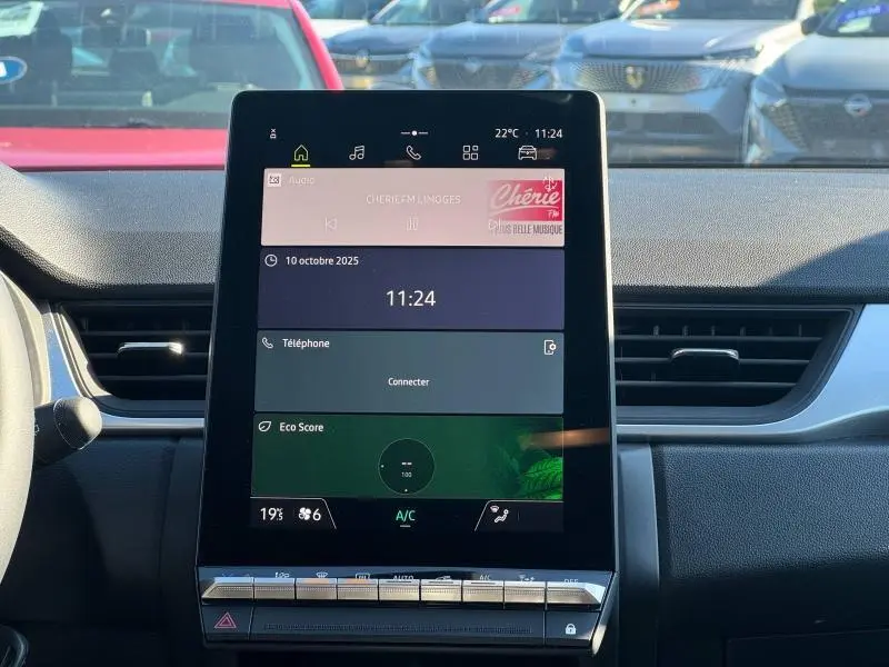 Écran tactile central du tableau de bord du Renault Captur 2025, avec commandes climatisation et radio visibles.