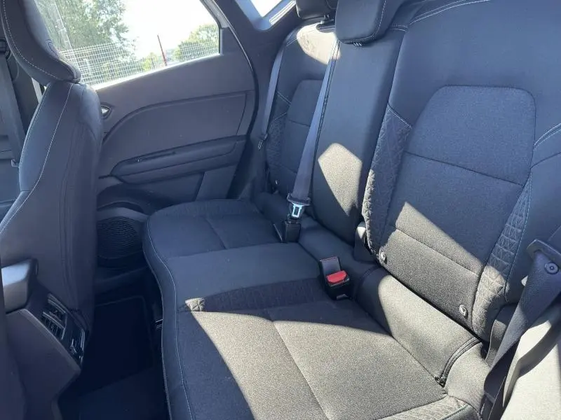Vue intérieure sur les sièges arrière noirs du Renault Captur 2025, montrant les ceintures de sécurité et les finitions tissu.