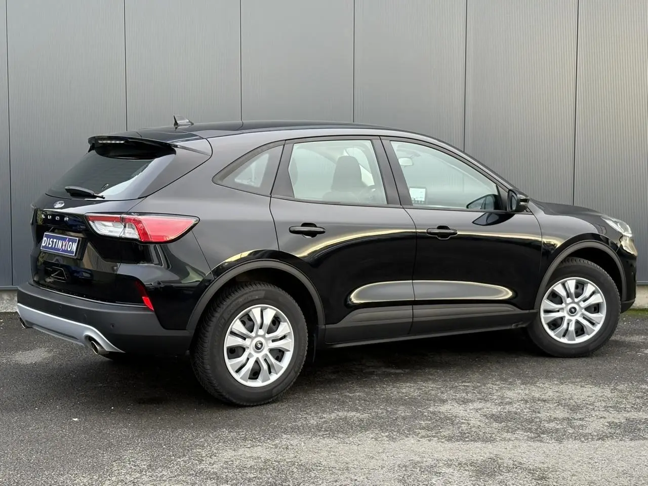 Vue de profil côté droit du Ford Kuga noir Obsidien 2024 avec attelage rétractable et jantes argentées.