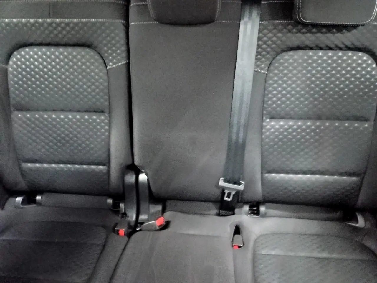 Vue rapprochée des sièges arrière noirs en tissu texturé du Ford Kuga 2024, avec ceinture de sécurité centrale visible.