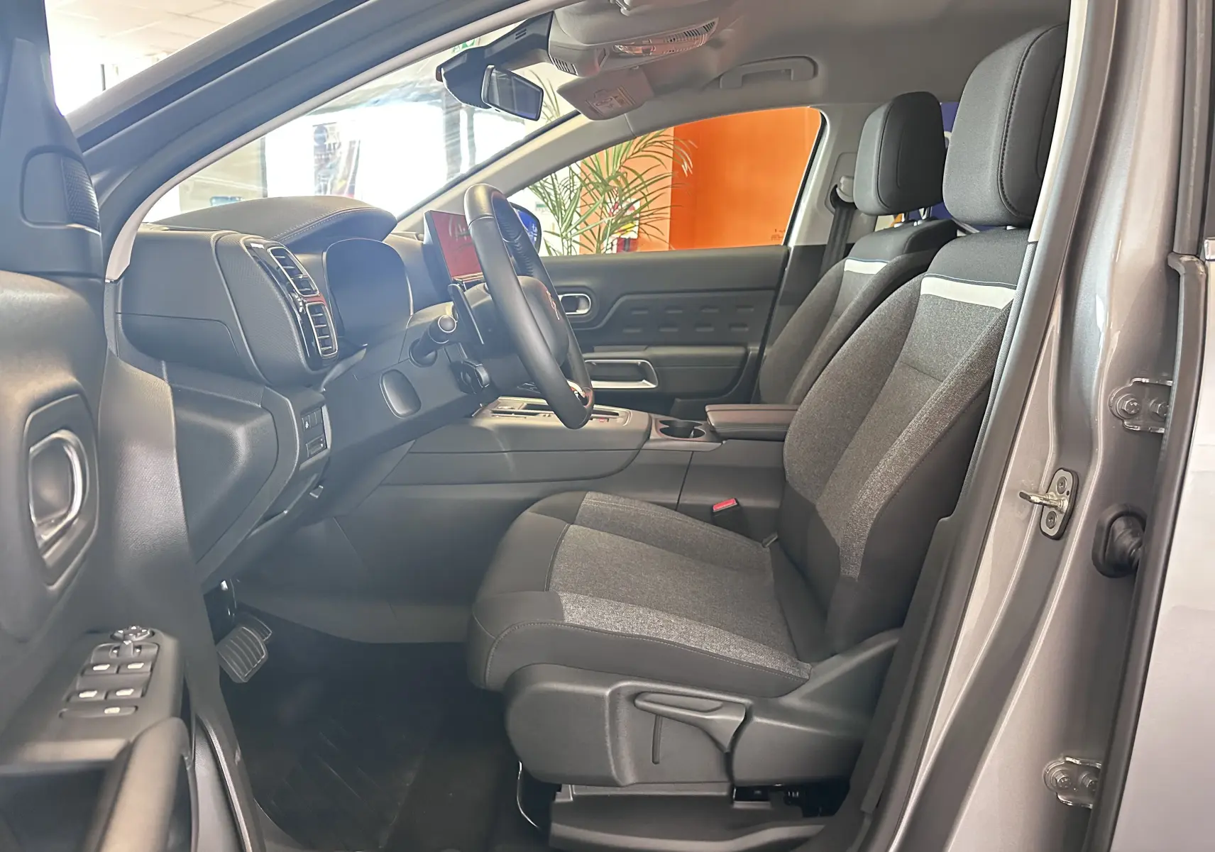 Vue intérieure côté conducteur du Citroën C5 Aircross gris Artense 2024, sièges tissu bicolore et volant cuir.