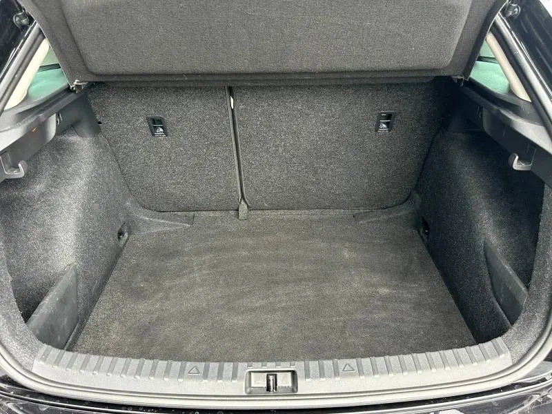 Coffre ouvert vu de face d'une Skoda Scala noir Magic nacré, montrant l'espace de chargement vide et les sièges arrière rabattables.