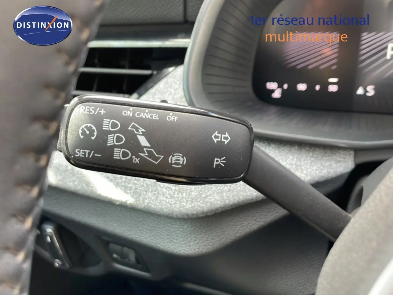Gros plan sur la commande de régulateur de vitesse au volant d'une Skoda Scala blanche Glacier, intérieur gris noir.