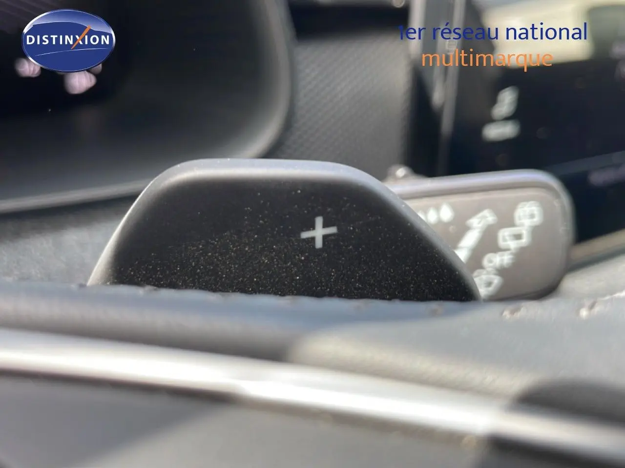 Gros plan sur la palette de changement de vitesse "+" du volant d'une Skoda Scala blanc glacier, intérieur gris-noir.