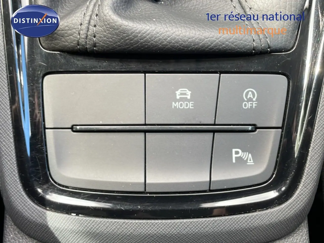 Gros plan sur les boutons de commande du mode de conduite et du stationnement assisté dans une Skoda Scala blanche Glacier 2025.