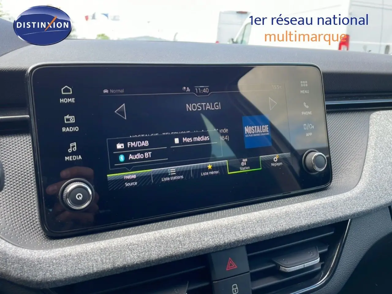 Écran tactile central du tableau de bord du Skoda Scala blanc glacier, affichant la radio Nostalgie en FM/DAB.