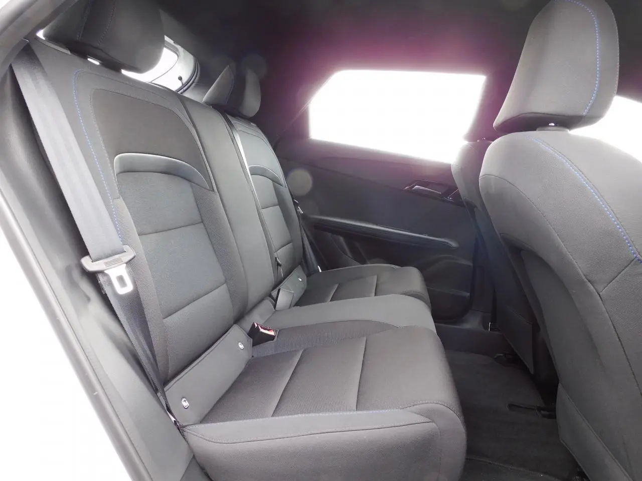 Vue latérale gauche de l'habitacle arrière du MG4 2023, sièges noirs avec surpiqûres bleues visibles.