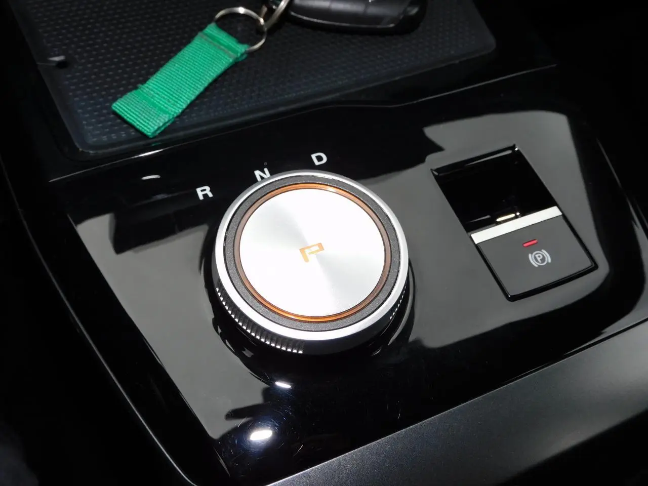 Gros plan sur la molette de sélection de vitesse et frein à main électronique du MG4 électrique noir brillant.