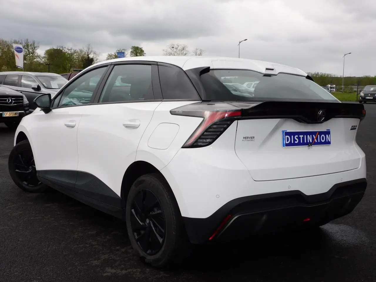 Vue 3/4 arrière droite d'une MG4 électrique blanche avec jantes noires et feux arrière LED distinctifs.