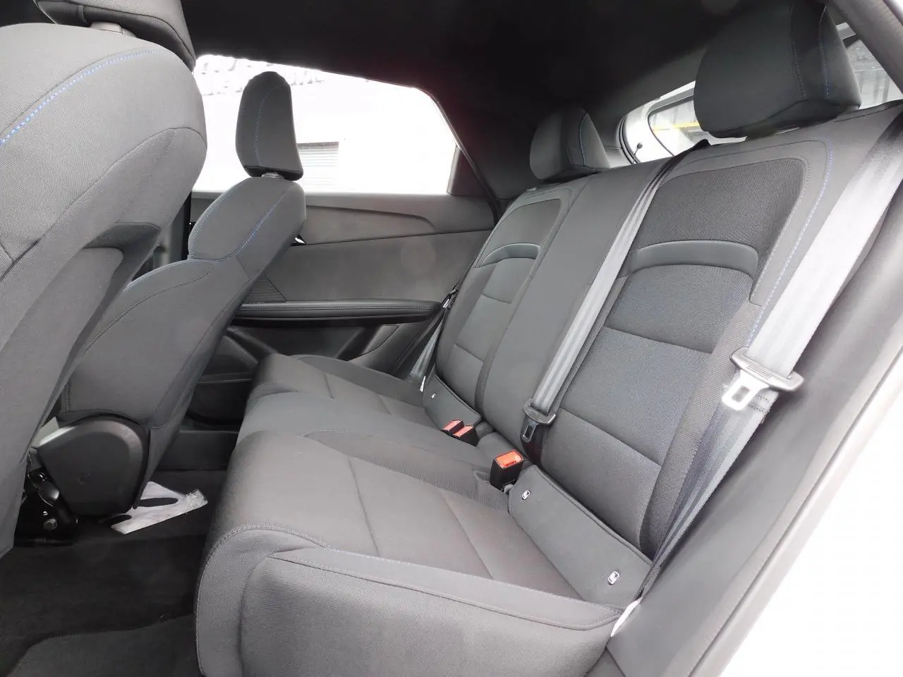 Vue latérale droite de l'habitacle arrière du MG4 2023 avec sièges tissu gris et ceintures de sécurité visibles.