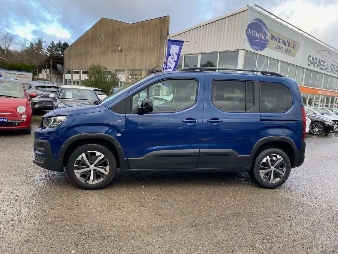 Profil côté gauche d'un Peugeot Rifter GT bleu métallisé 2023 avec jantes alliage et protections noires.