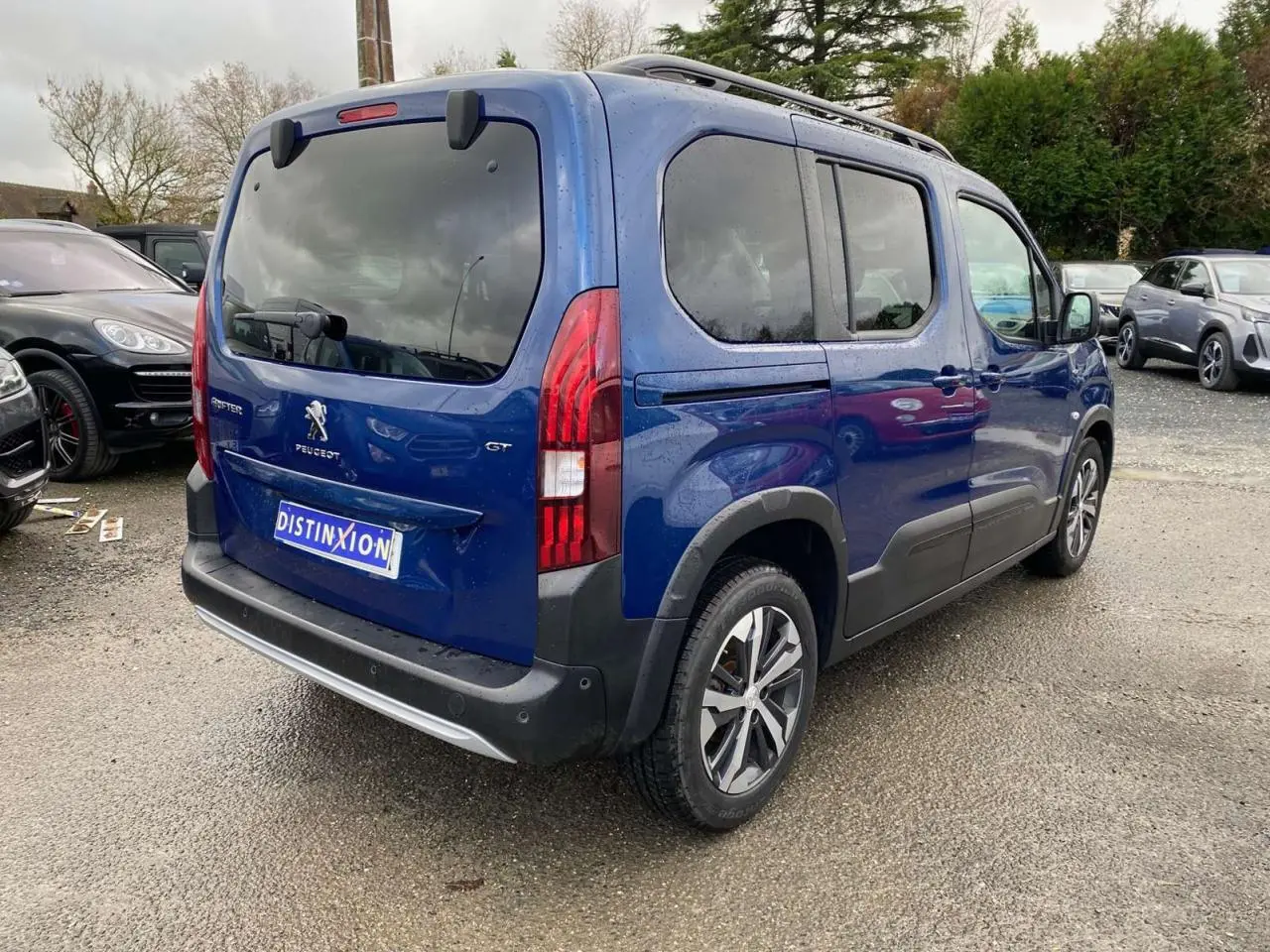 Vue 3/4 arrière droite d'un Peugeot Rifter GT bleu métallisé avec jantes alliage 17 pouces et vitres surteintées.