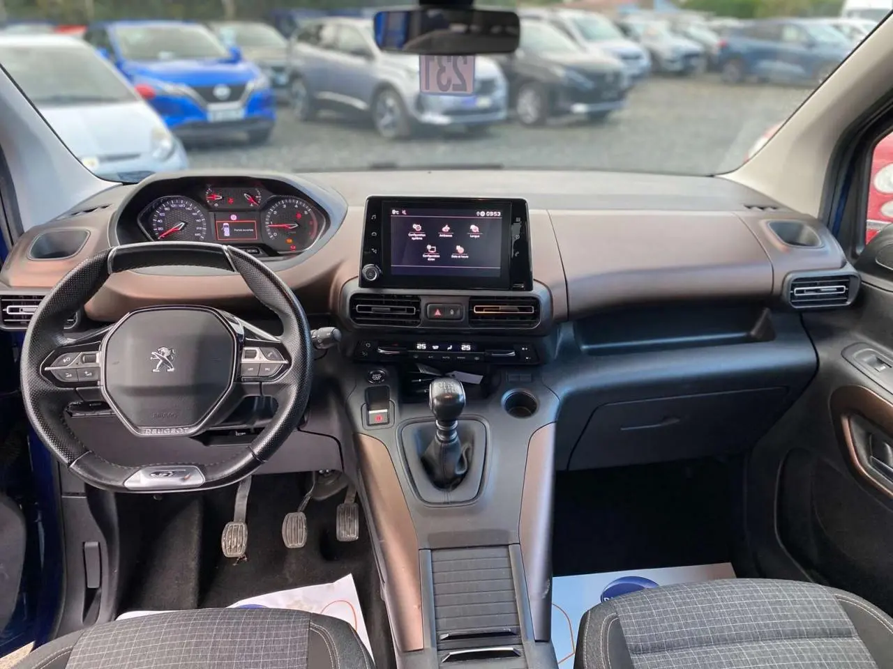 Vue intérieure avant du Peugeot Rifter GT bleu 2023, avec tableau de bord moderne et boîte manuelle.
