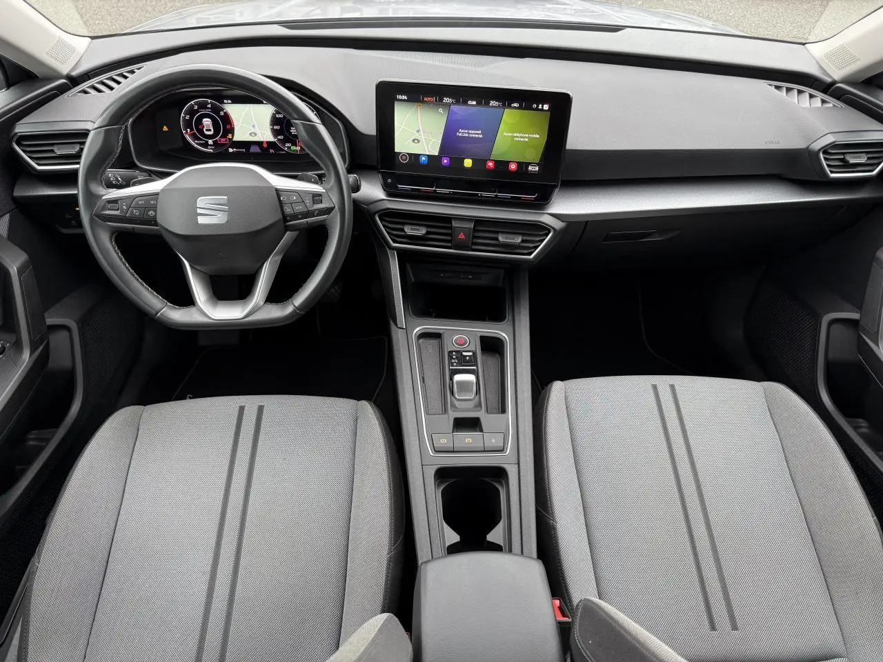 Intérieur de la SEAT Leon 2022 vu de dessus, avec tableau de bord digital et sièges gris clair à rayures.