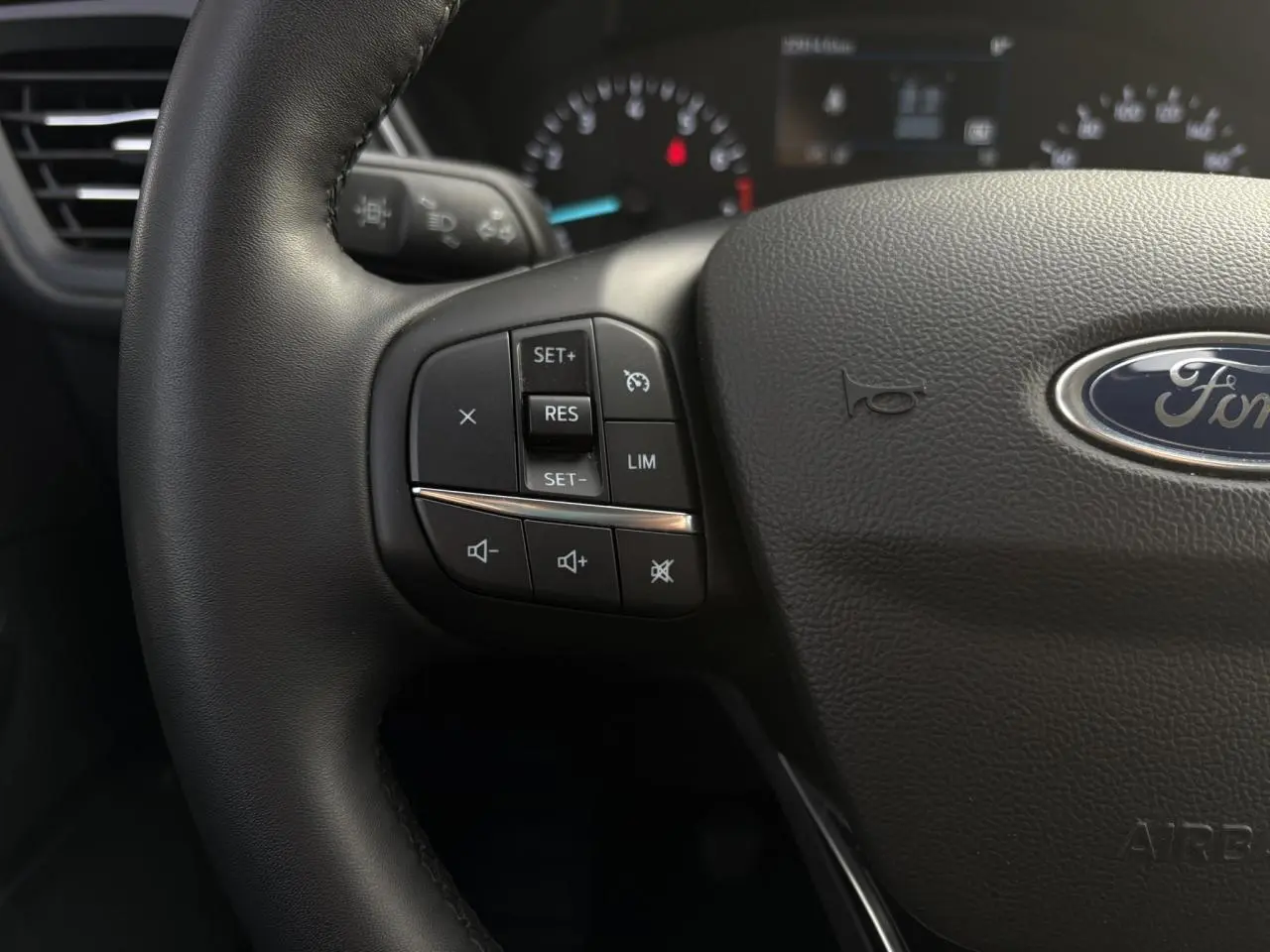 Gros plan sur le volant multifonctions en cuir du Ford Kuga 2024, avec commandes de régulateur et volume visibles.