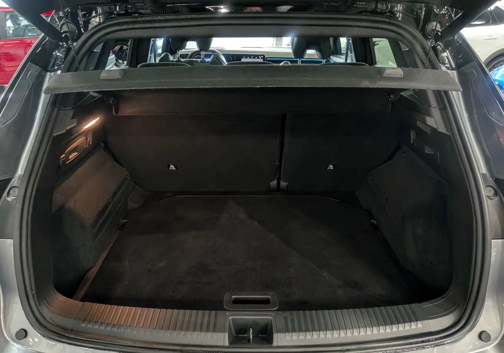 Coffre ouvert vu de l'arrière d'un Renault Austral gris schiste avec toit noir, intérieur spacieux et tapis noir.