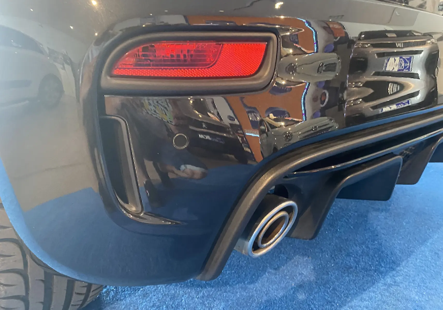 Gros plan sur le feu arrière droit et la sortie d'échappement d'une ABARTH 595 noire, finition brillante.