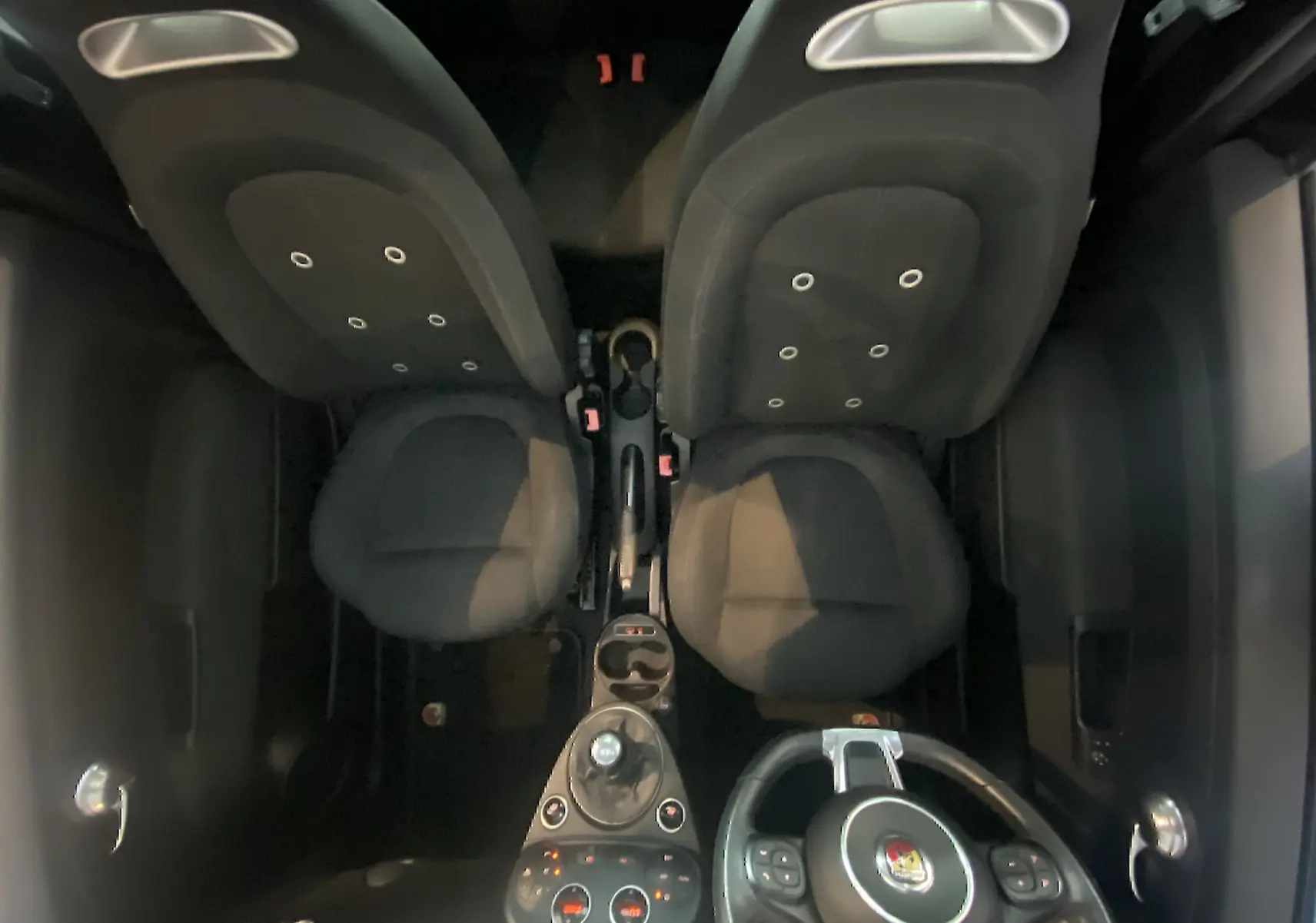 Vue plongeante sur l'intérieur noir de l'Abarth 595 2018, montrant sièges, volant et console centrale avec levier de vitesse.