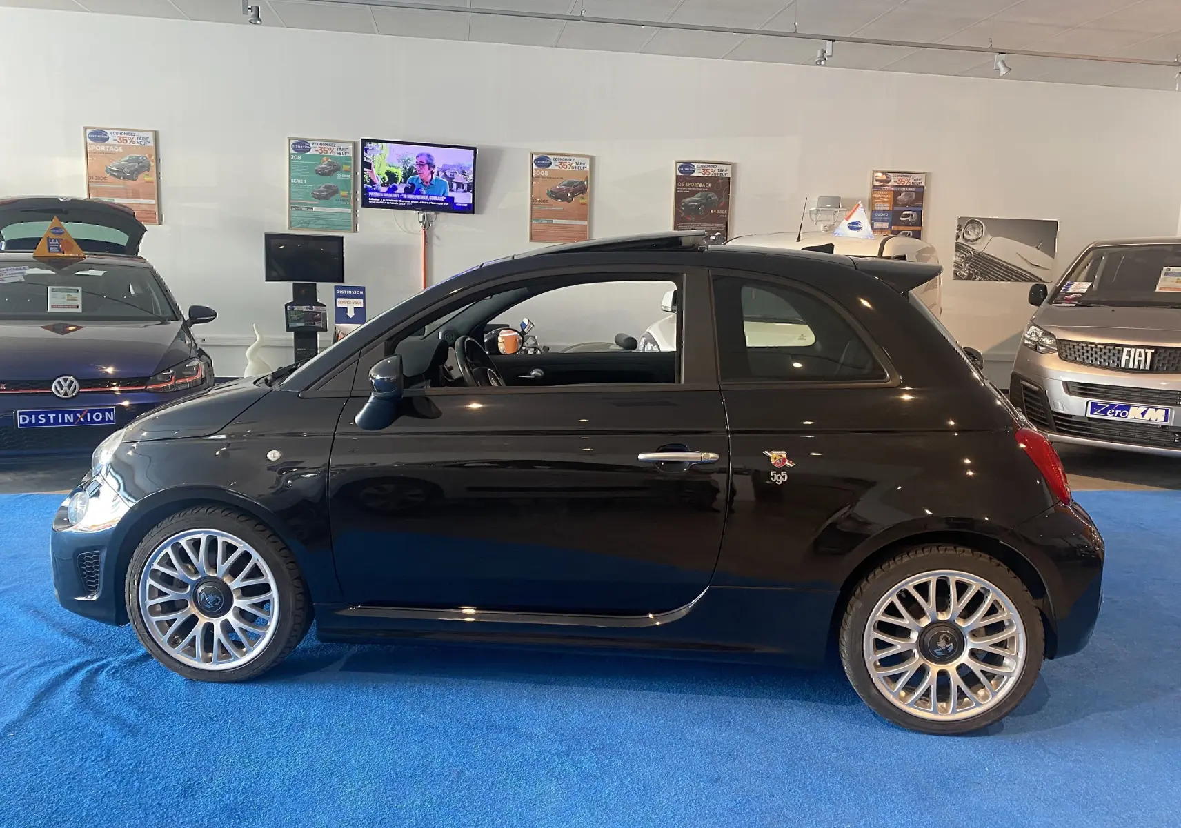 Profil côté gauche de l'Abarth 595 noire 2018 avec jantes alu 17 pouces et toit ouvrant électrique en showroom.
