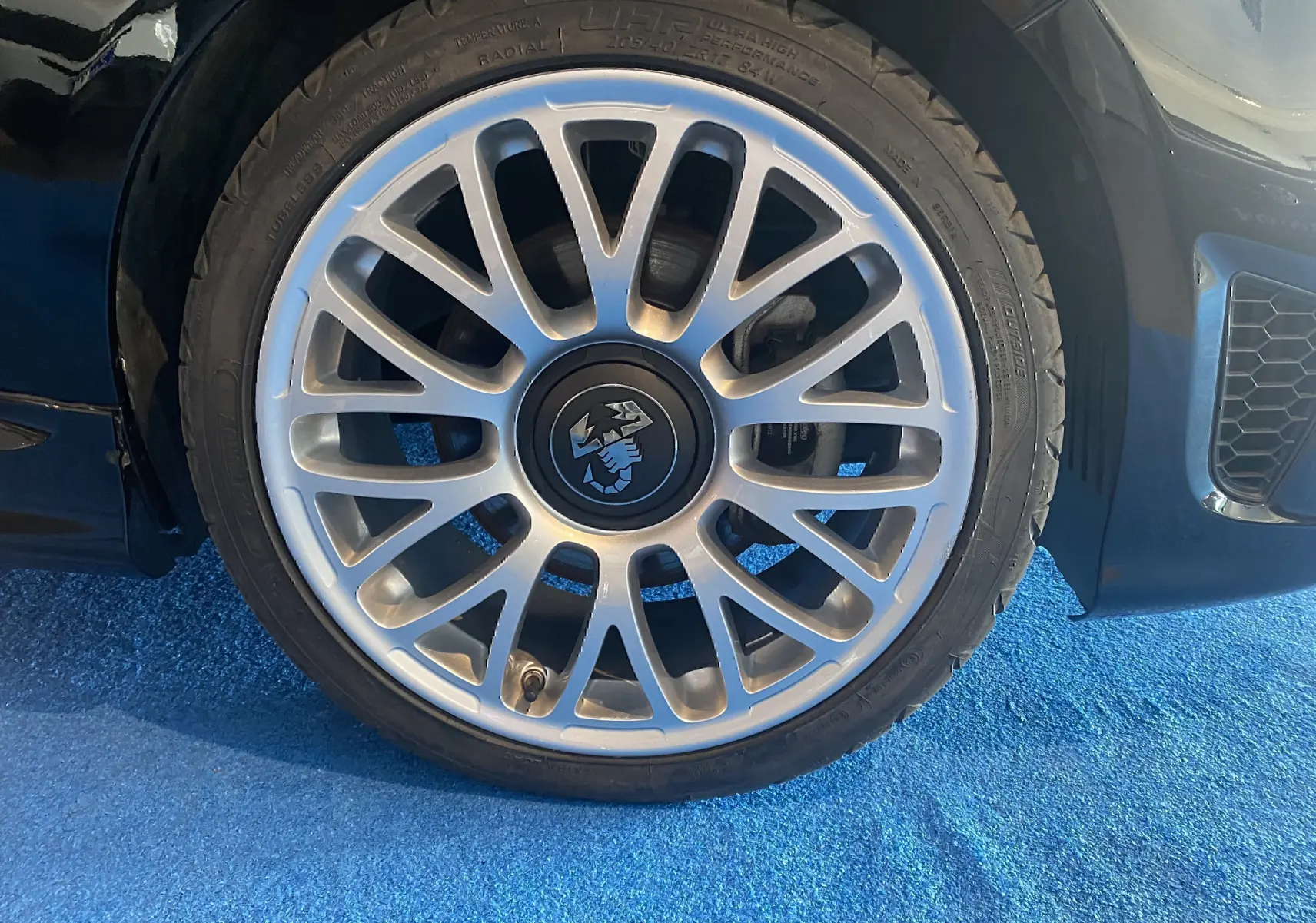 Gros plan sur la jante alu argentée de 17 pouces avec logo Abarth sur une roue avant droite noire.