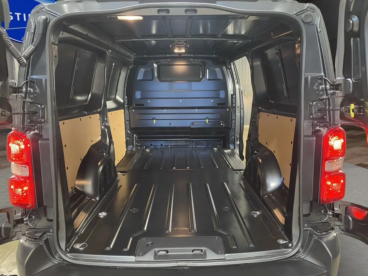 Vue arrière du Citroën Jumpy Fourgon gris platinium 2024, montrant l'espace de chargement vide et les feux arrière allumés.