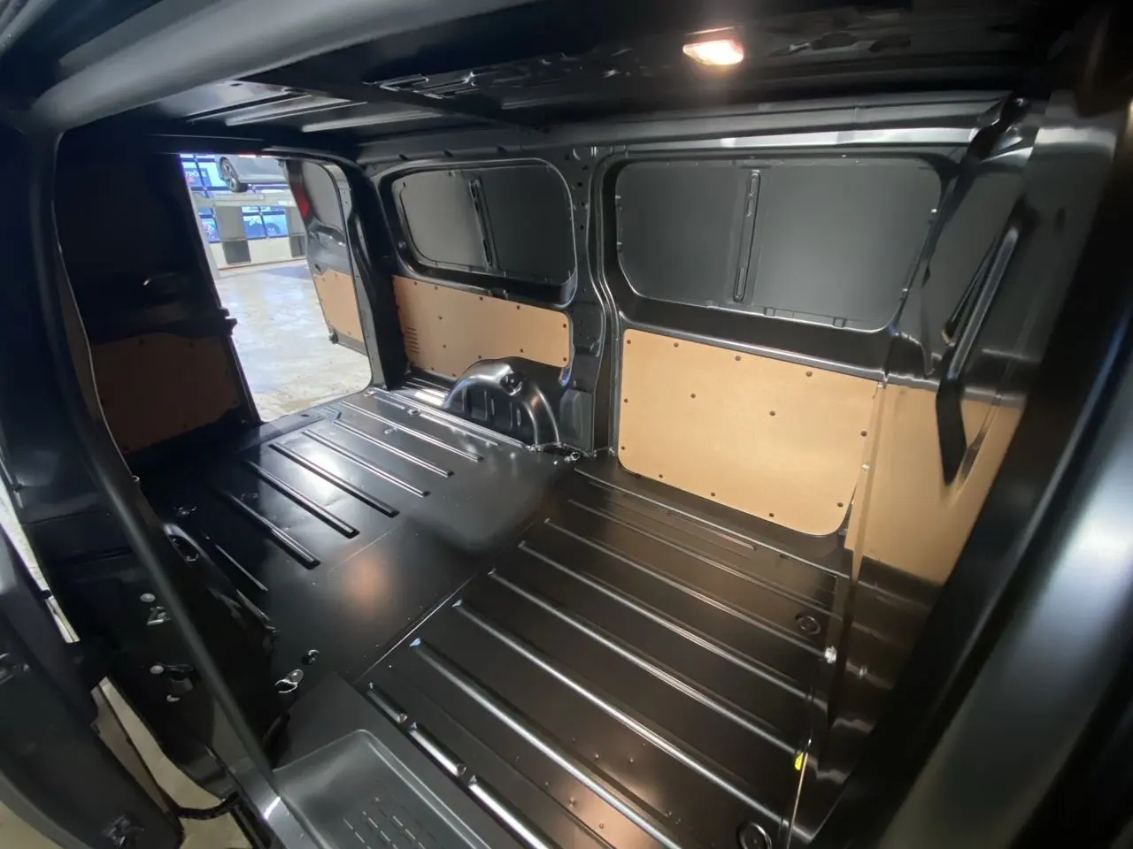 Intérieur du fourgon Citroën Jumpy gris platinium, vue de l'espace de chargement avec parois tôlées et plancher métallique.