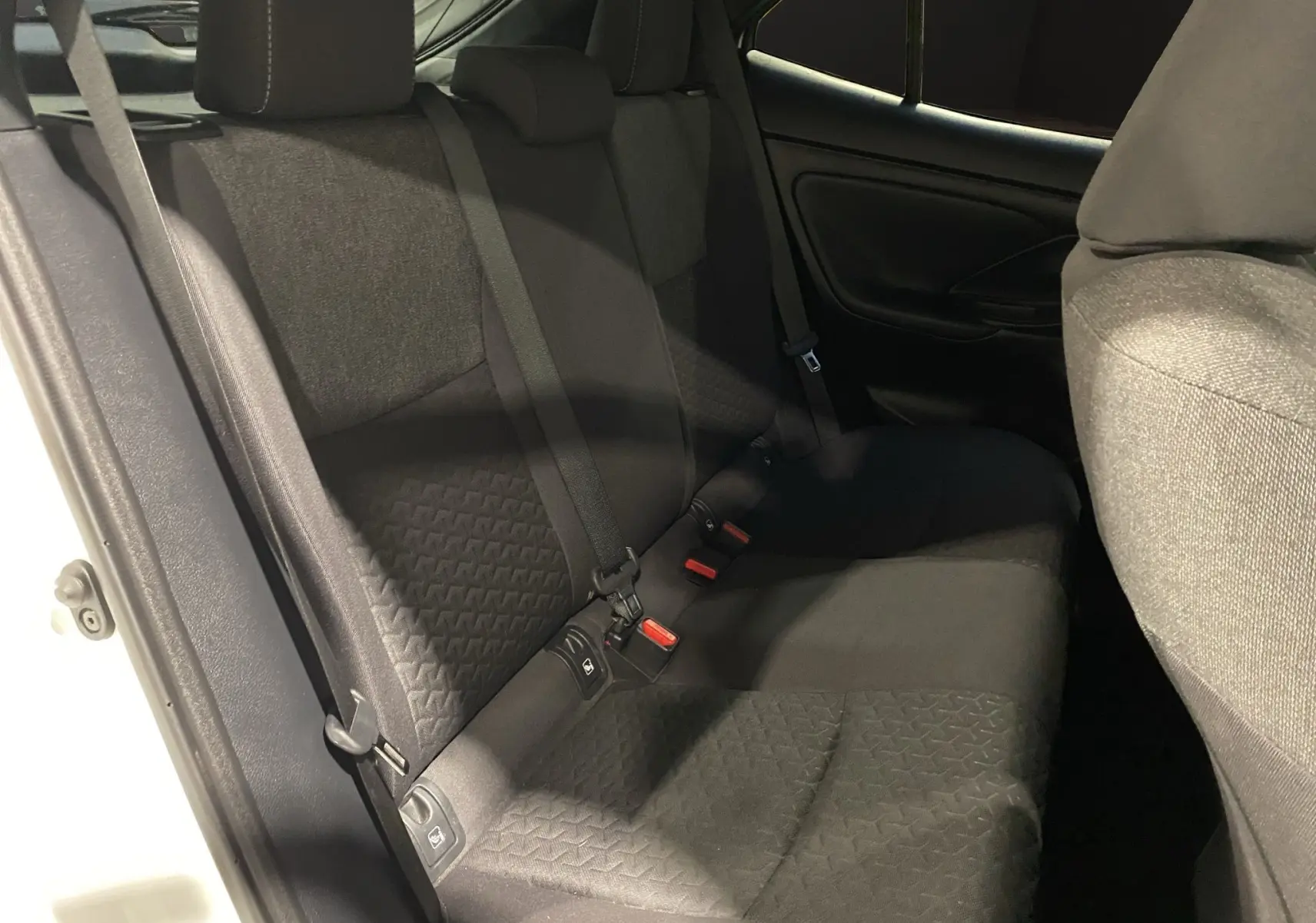 Vue côté gauche de la banquette arrière noire en tissu de la Toyota Yaris Cross 116H Design blanche.