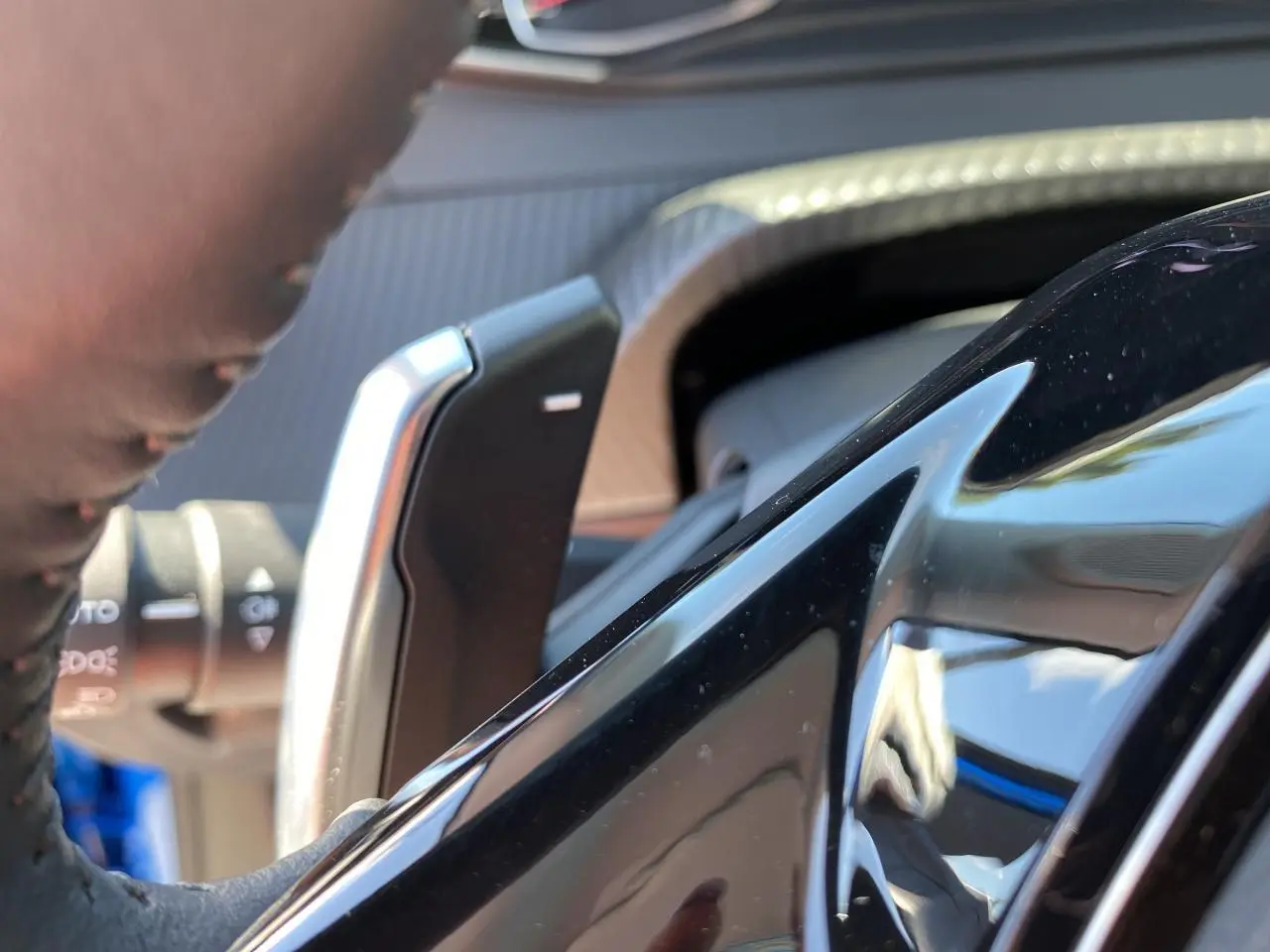 Gros plan sur la palette de changement de vitesses au volant d'un Peugeot 2008 bleu Vertigo, intérieur moderne.