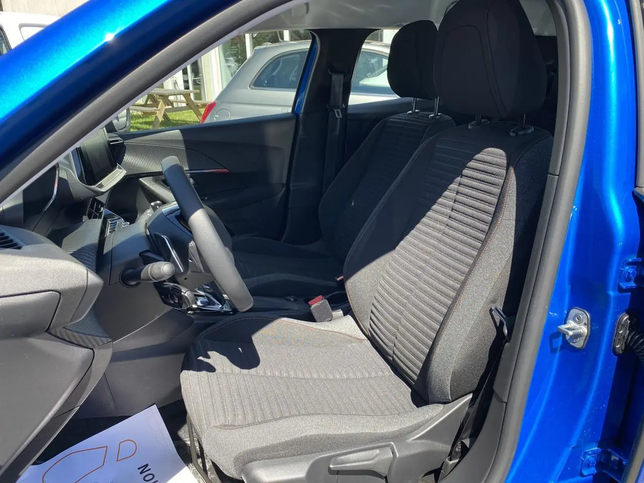 Vue intérieure côté gauche du Peugeot 2008 bleu Vertigo, montrant les sièges avant et le tableau de bord moderne.