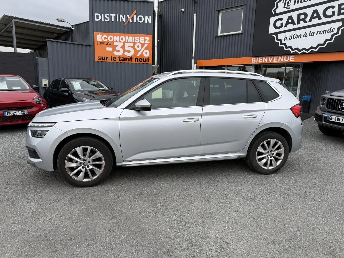 Profil côté gauche d'un Skoda Kamiq gris métallisé 2022 garé devant un garage avec jantes alliage 17 pouces.