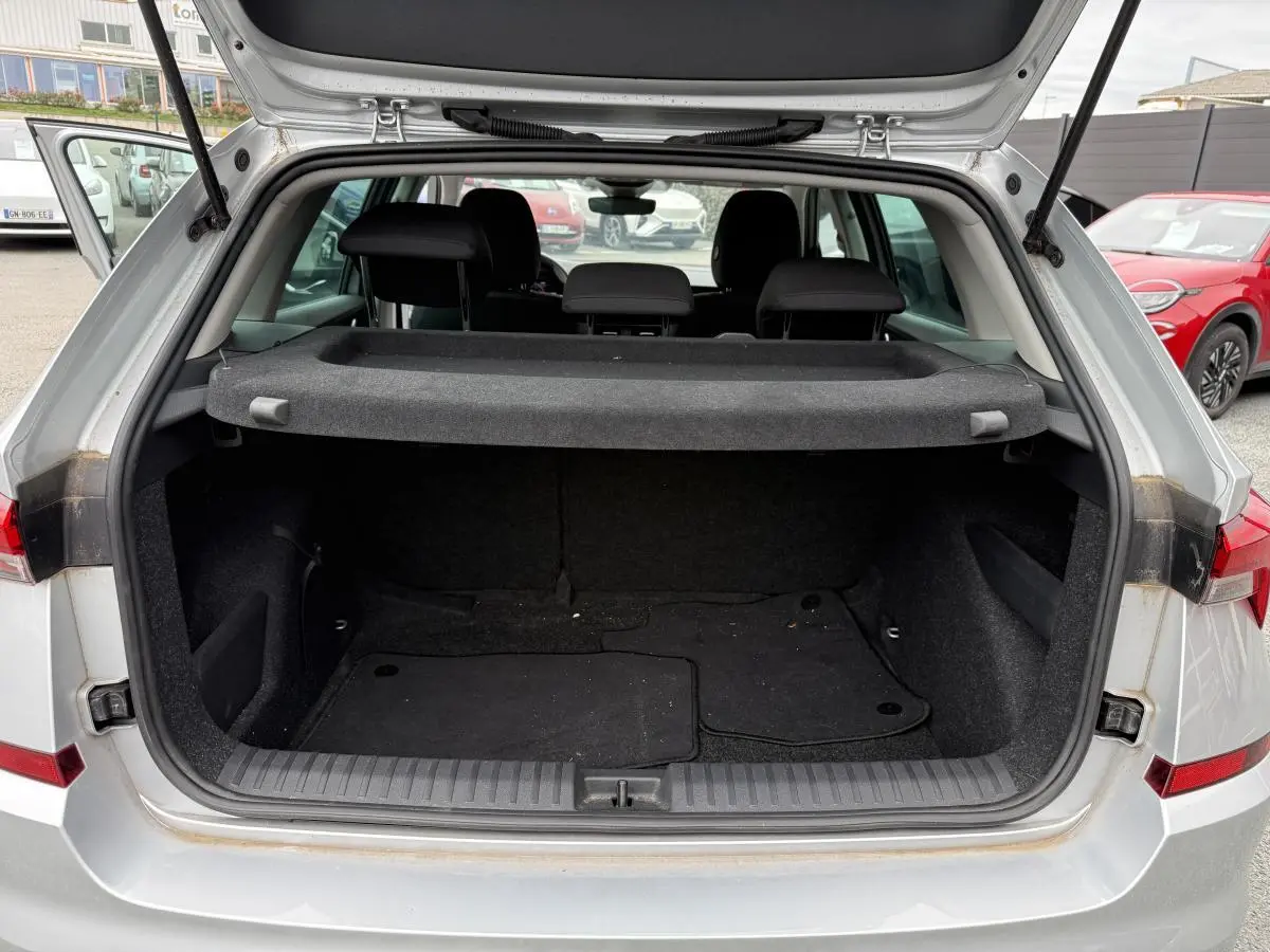 Coffre ouvert gris métallisé d'un Skoda Kamiq 2022 avec tablette cache-bagages et sièges arrière noirs visibles.