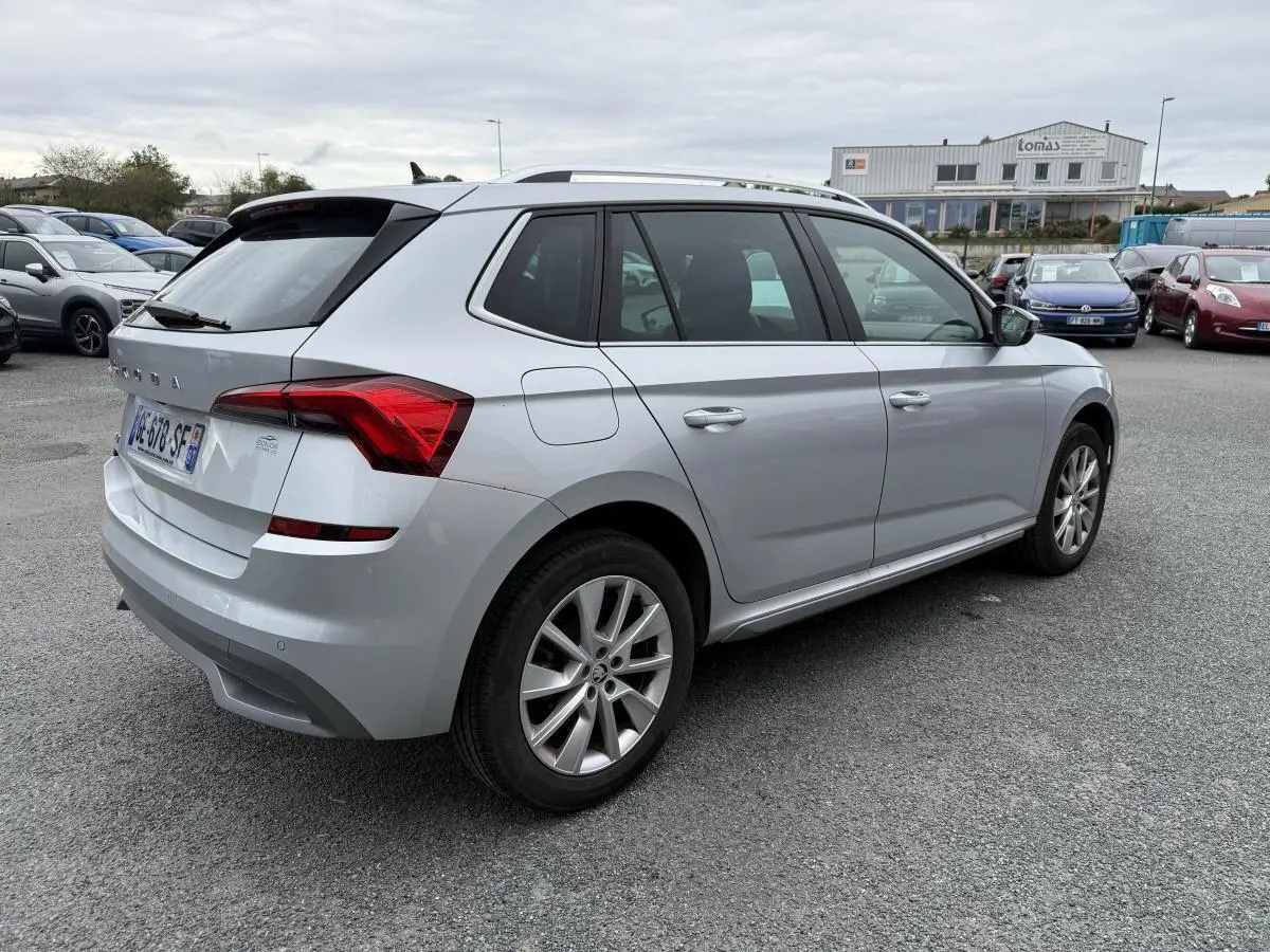 Vue 3/4 arrière droite d'un Skoda Kamiq gris métallisé avec jantes alliage 17'' sur un parking extérieur.