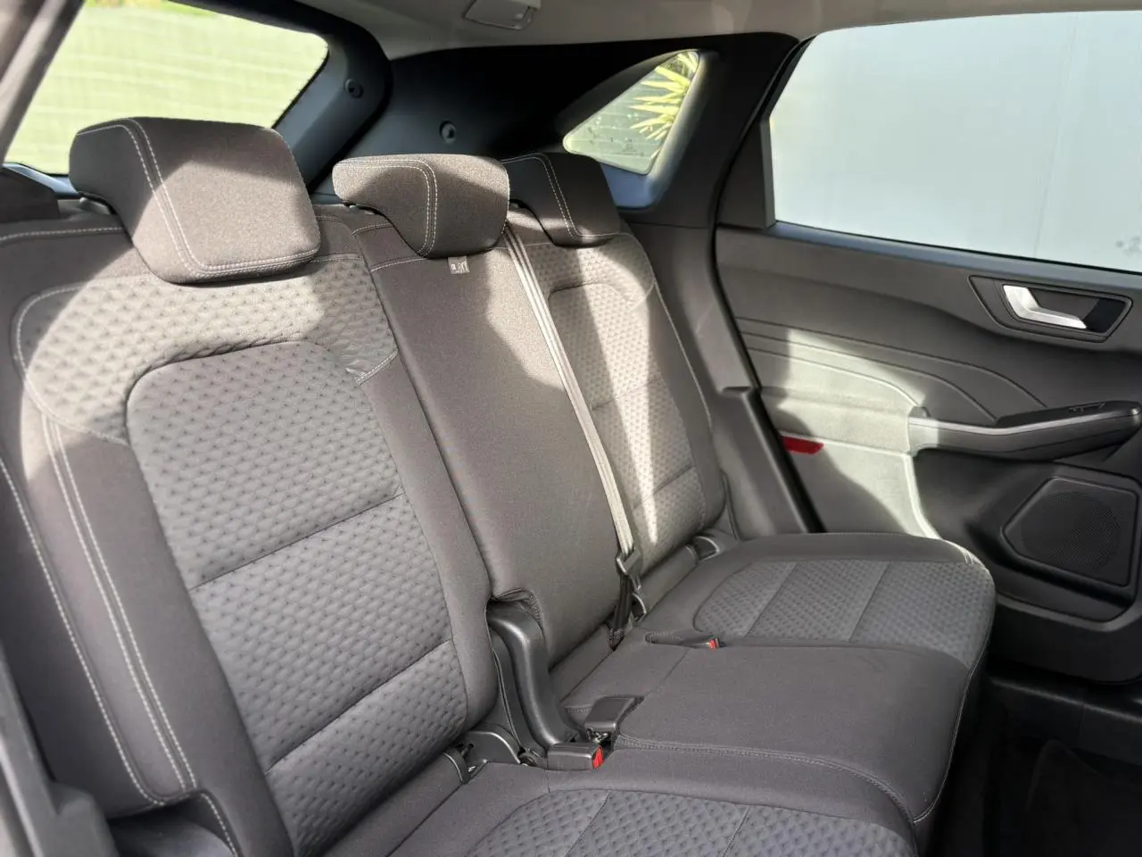 Vue latérale droite des sièges arrière gris foncé du Ford Kuga 2024, montrant les appuie-têtes et la portière intérieure.