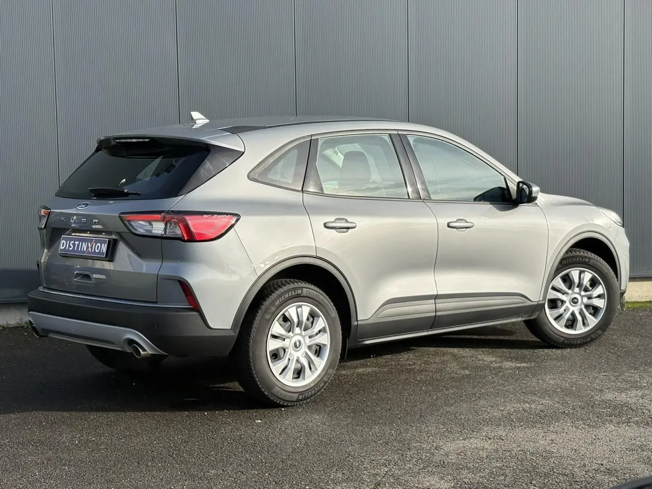 Vue 3/4 arrière droite d'un Ford Kuga 2024 gris Solar avec feux arrière LED et jantes alliage.