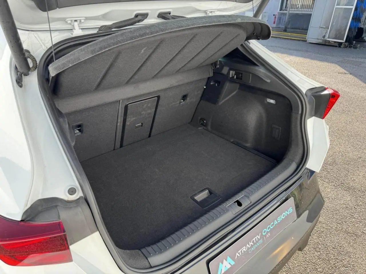 Coffre ouvert vu de l'arrière d'une CUPRA Formentor blanc nacré avec intérieur noir et feux arrière rouges.