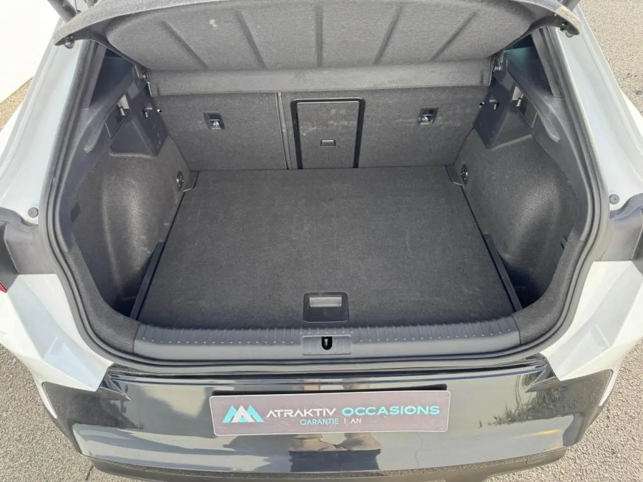 Coffre ouvert vu de l'arrière d'une CUPRA Formentor blanc nacré avec toit noir, montrant un espace de chargement vide.