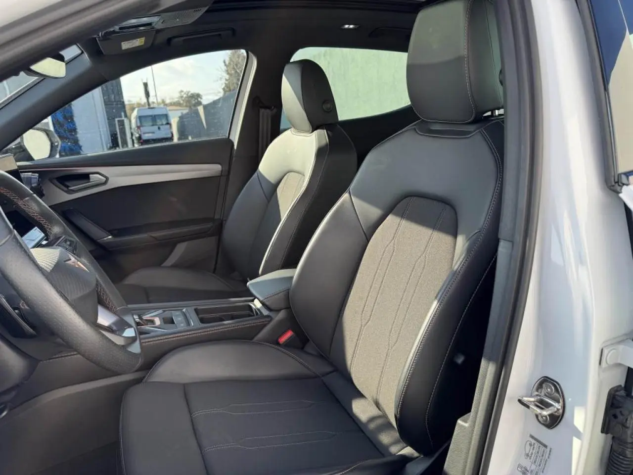 Vue intérieure côté conducteur du CUPRA Formentor blanc nacré, sièges sport noirs avec surpiqûres contrastées.