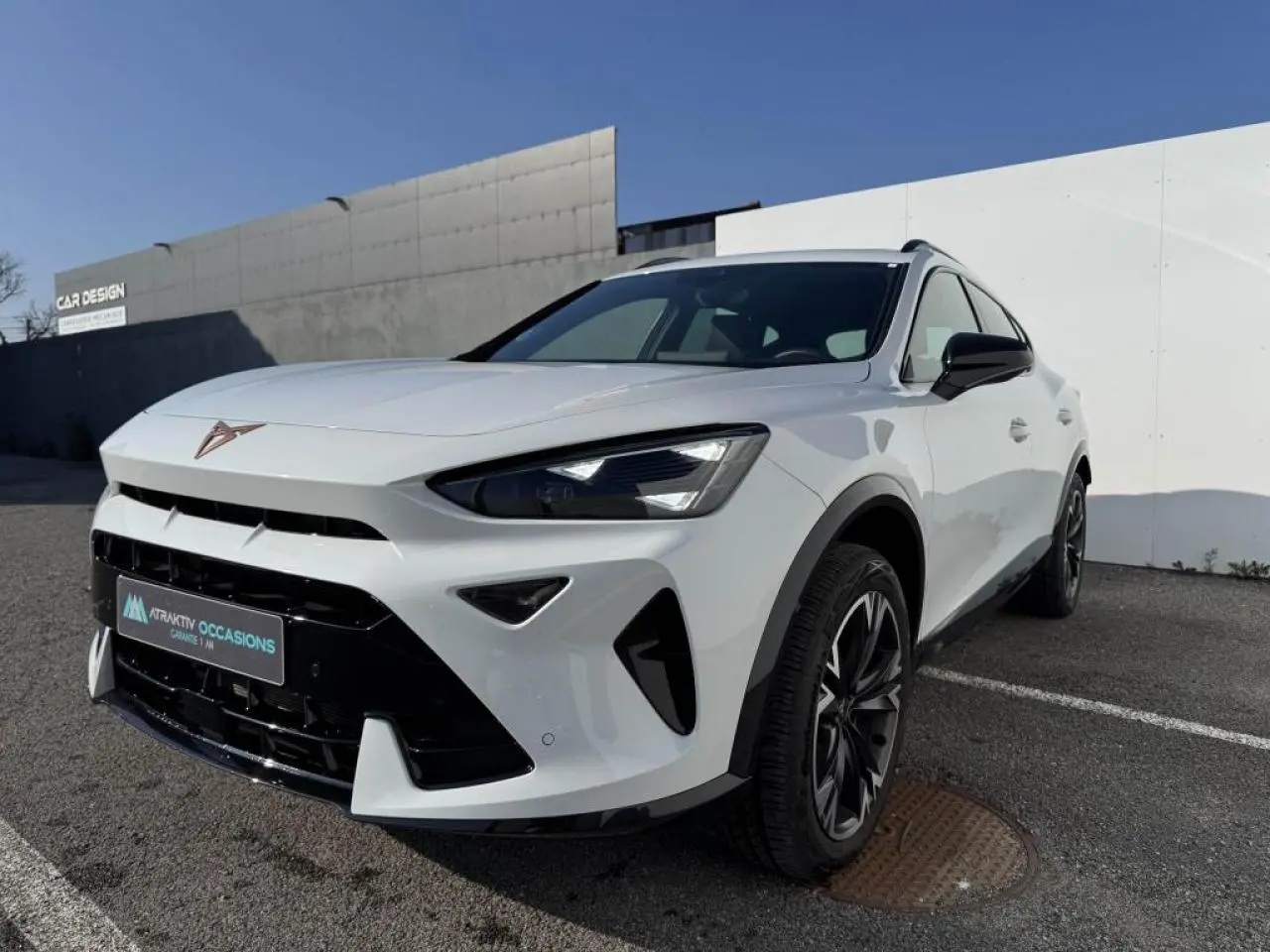 Vue 3/4 avant droit du CUPRA Formentor blanc nacré avec toit noir et jantes alliage noires, sur parking extérieur.