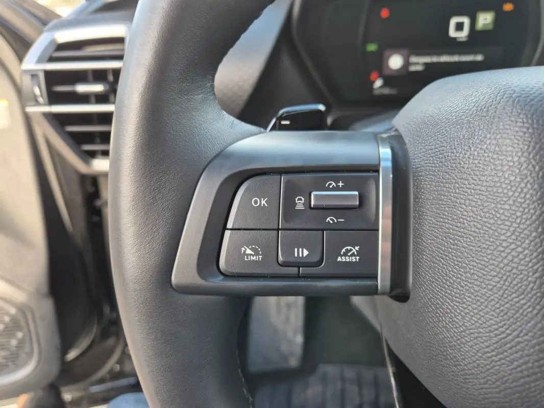 Gros plan sur les commandes du volant cuir de la Citroën C5 X noire 2024, avec régulateur et assistant de conduite.