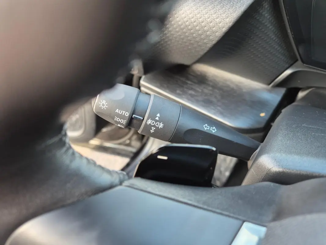 Gros plan sur la manette de commande des phares et clignotants dans l’habitacle noir d’une Citroën C5 X 2024.