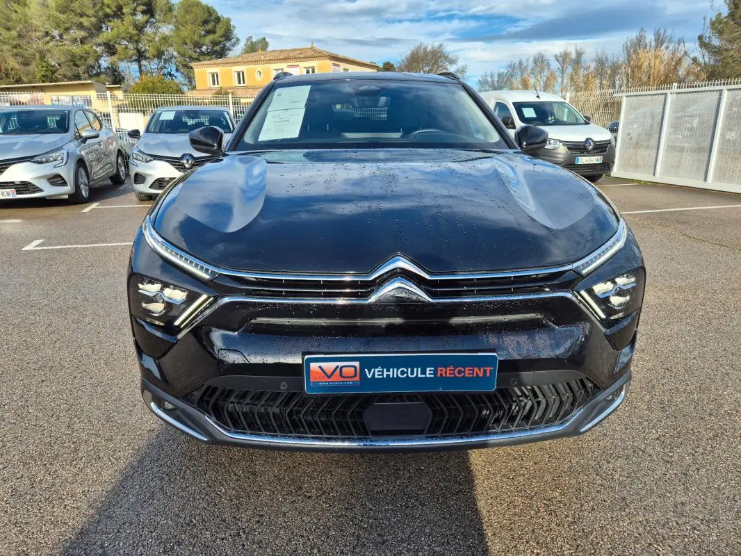 Vue avant d'une Citroën C5 X noire 2024 avec calandre chromée et feux LED distinctifs, stationnée en extérieur.