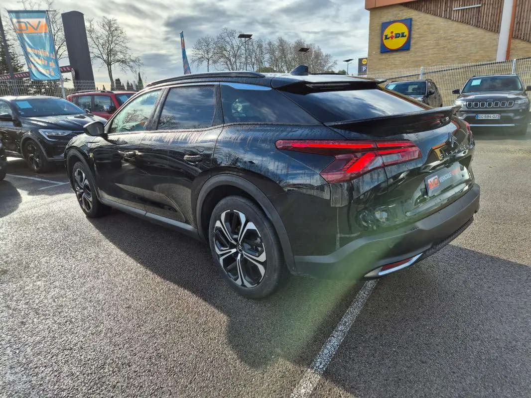 Vue 3/4 arrière droite d'une Citroën C5 X noire 2024 avec jantes alliage 19 pouces et antenne requin.