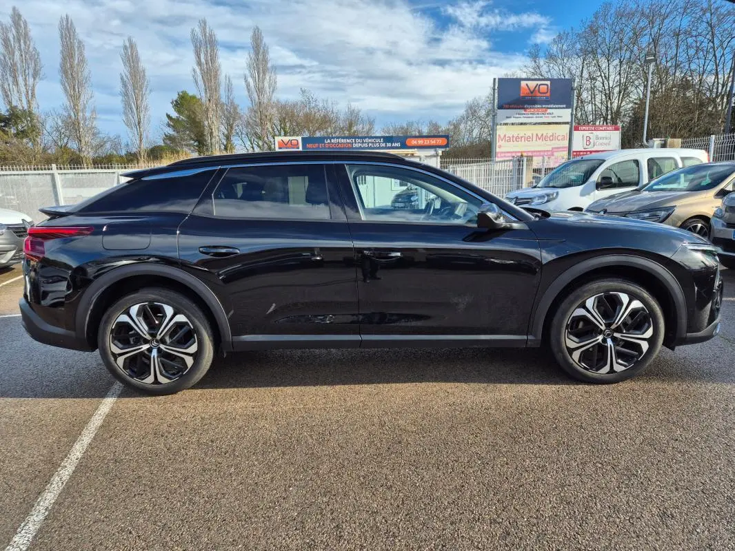 Vue de profil côté gauche d'une Citroën C5 X noir 2024 avec jantes alliage 19 pouces sur parking extérieur.