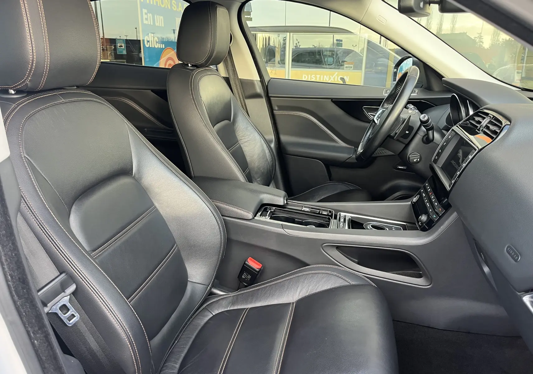 Vue intérieure côté gauche du Jaguar F-PACE 240D Prestige 2018 blanc, sièges cuir noir avec surpiqûres contrastées.