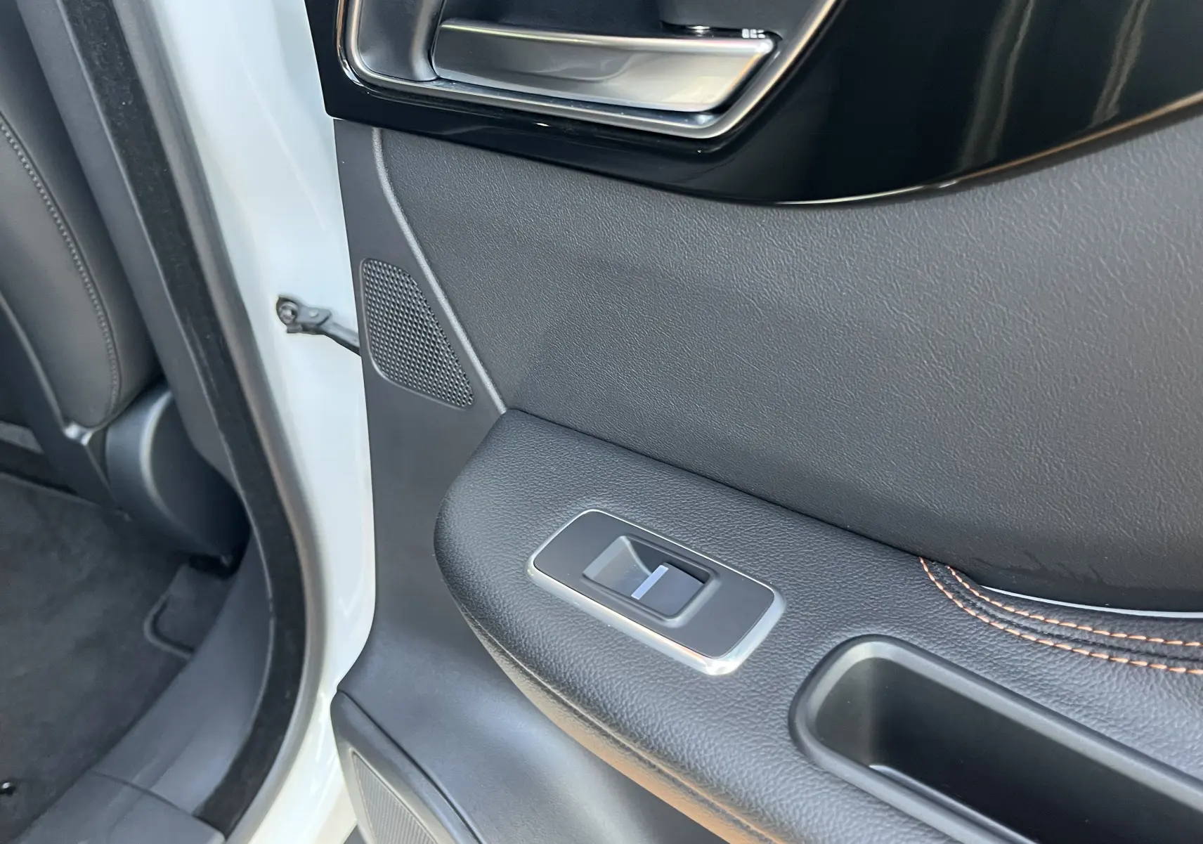 Gros plan sur la porte arrière gauche blanche d’un Jaguar F-PACE 240D Prestige 2018, avec bouton de fenêtre et surpiqûres orange.