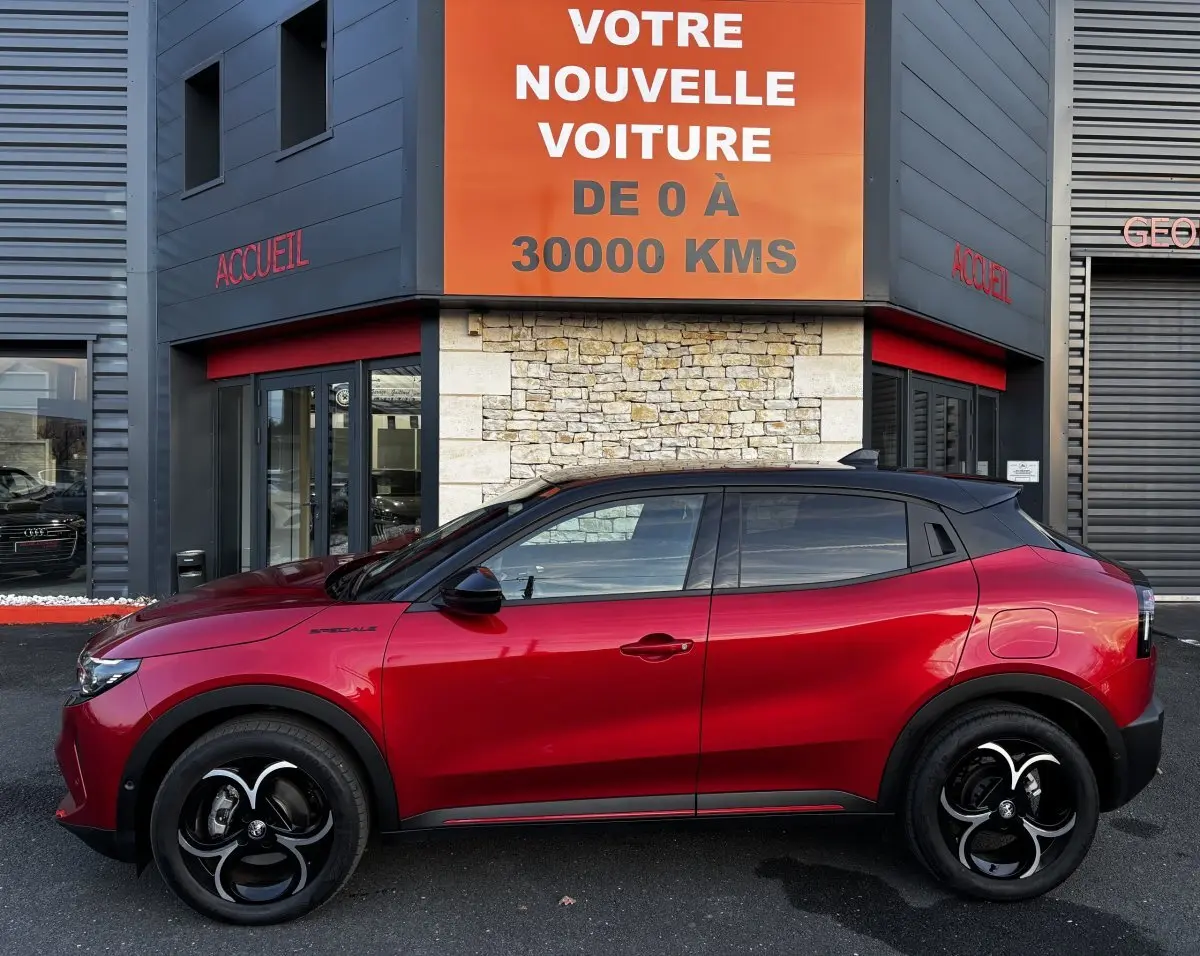 Profil droit de l'Alfa Romeo Junior rouge 2024 avec toit noir, jantes noires et détails sportifs visibles.